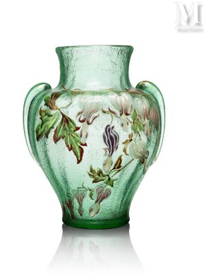 un vase vert sur lequel sont peints des fleurs et des feuilles