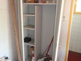 a tall cabinet with a microwave on top of it