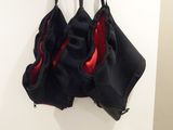 black and red bralette hanging on a hook on a wall