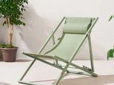 une chaise de jardin verte posée sur un tapis, à côté d'une plante en pot