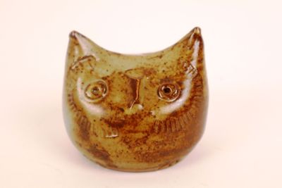 a brown and black cat figurine sitting on a white surface
