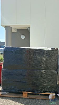 une grande boîte noire posée sur une palette à côté d'un bâtiment