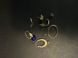 some gold rings and a blue bead on a black surface