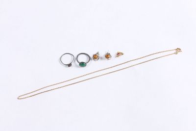 trois bagues différentes et un collier posés sur une surface blanche