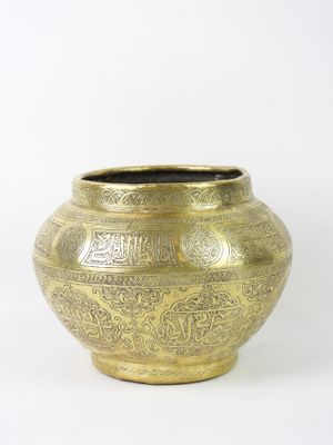 a gold vase that is sitting on a white surface