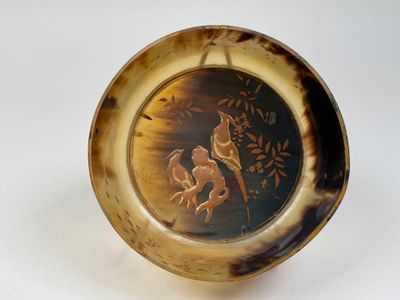 une assiette marron sur laquelle est représenté un oiseau et des fleurs