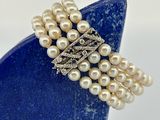 broche en perles et diamants sur un support bleu