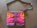 sac à main violet et rose avec des touches orange sur un fond marron