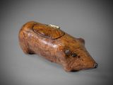 a small wooden pig figurine on a gray surface