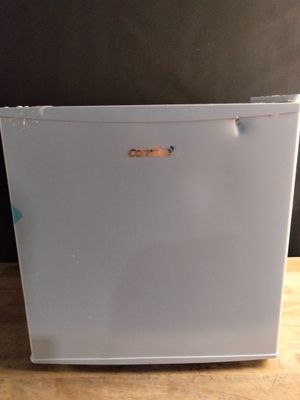 un petit réfrigérateur blanc posé sur une table en bois