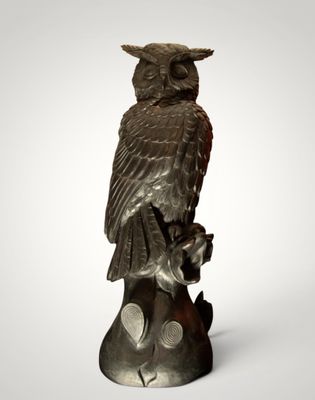 an owl statue sitting on top of a tree branch