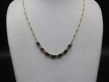 a gold necklace with blue sapphires on a mannequin