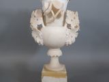 un vase blanc orné de fleurs, posé sur un socle