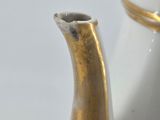 a white and gold vase with a gold handle