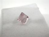a close up of a pink diamond sitting on top of a white surface