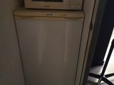 un petit réfrigérateur blanc et un micro-ondes dans une petite pièce