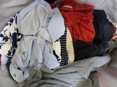 a pile of clothes sitting on top of a bed