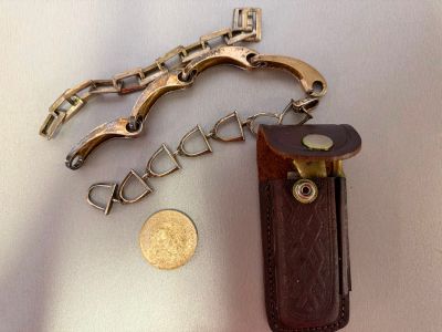 a keychain with a gun on it next to a coin