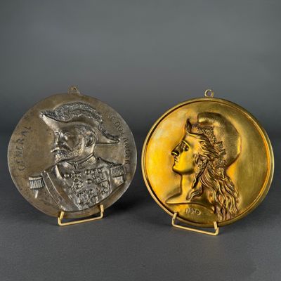 two gold and silver medallions of a man and a woman