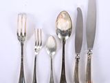 five forks, a knife, a spoon, and a knife on a white surface
