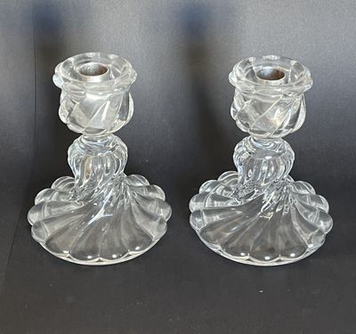 une paire de bougeoirs en verre transparent posés sur une surface noire
