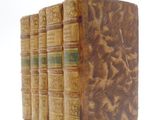 three old books are stacked on top of each other on a white surface
