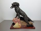 statue of a dog sitting on a block of cheese with a piece of cheese in its mouth