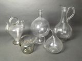 five glass vases and a glass pitcher on a table