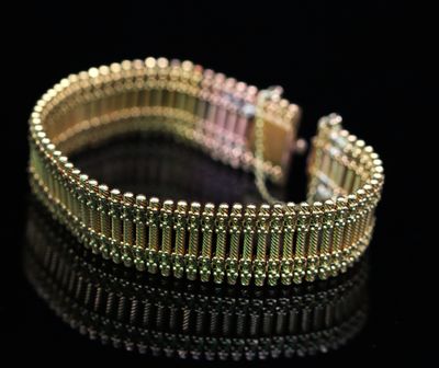 gros plan d'un bracelet en or sur une surface noire