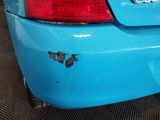the rear end of a blue car with rust on it