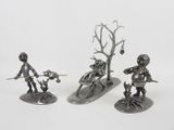 three silver metal figurines of a man and a woman on a snowboard