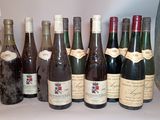 bottles of wine are lined up on a shelf in front of a vase