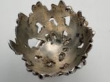 a silver bowl that has a leaf design on it