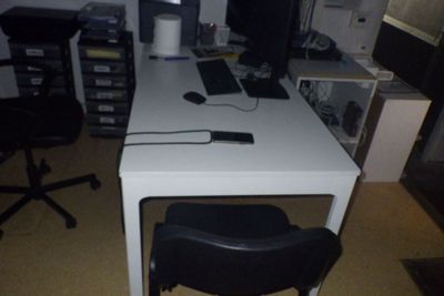 un bureau blanc avec une chaise noire et un ordinateur posé dessus