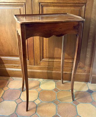 une petite table en bois avec un plateau en verre, posée sur un sol carrelé