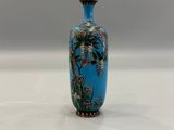 a blue vase sitting on a table with a bird on it