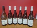 six bouteilles de vin sont alignées sur une table en bois
