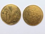 deux pièces d'or posées sur une surface blanche ; l'une représente un homme et l'autre une femme