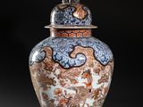 an orange and blue vase with a bird on top of it