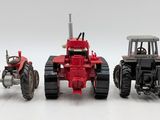 three toy tractors sitting next to each other on a white surface