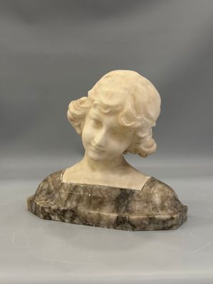 un buste en marbre blanc représentant une femme, posé sur un rocher