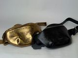 two black and gold fanny bags sitting next to each other on a white surface