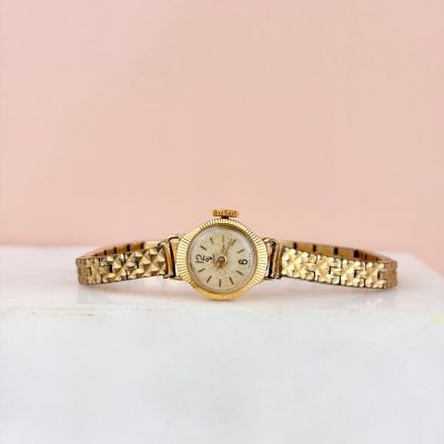 une photo d'une montre en or posée sur une boîte blanche