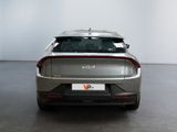 the rear end of a silver car in a room with a white wall