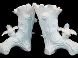 a pair of white vases that have birds on them