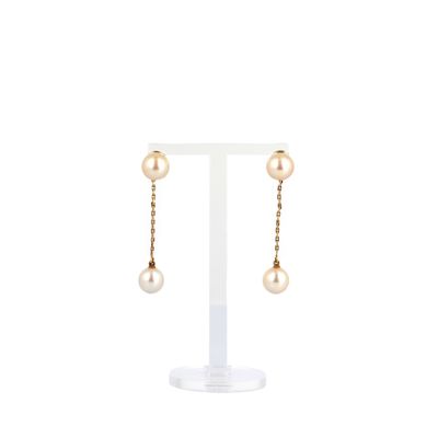 une paire de boucles d'oreilles en perles et en or, présentée sur un présentoir