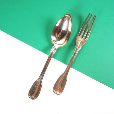 deux cuillères en argent et une fourchette posées sur un plateau vert et blanc