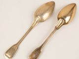 pair of silver spoons on a white surface with a white background