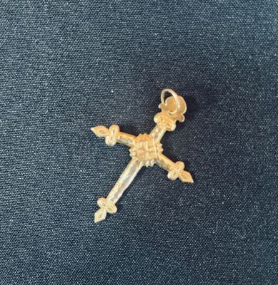 une croix en or surmontée d'une couronne, posée sur un tissu bleu