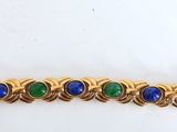 a close up of a gold bracelet with blue and green stones
